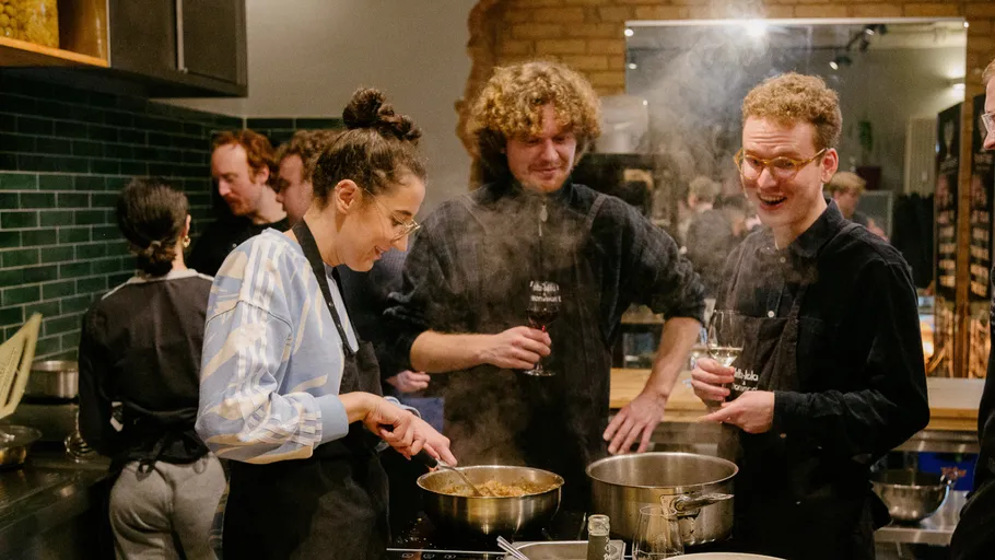 Group cooking together in kitchen, smiling.