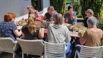Gruppe von Menschen, die am Tisch im Freien essen.