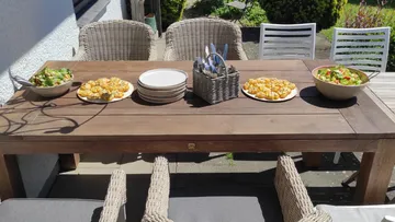 Esstisch im Freien mit Salaten und Gebäck.