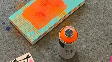 Orangefarbene Sprühfarbendose auf dem Teppich.