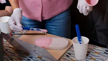 Person pouring pink mixture into mold.