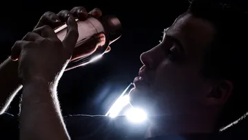 Person schüttelt Cocktail-Shaker, Szene mit Hintergrundbeleuchtung.