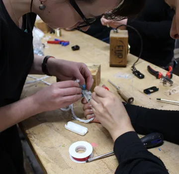 Hands assembling electronics on a workbench.