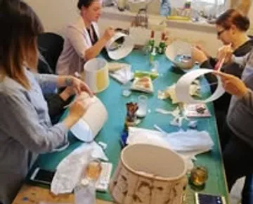 People crafting lampshades at a table workshop.