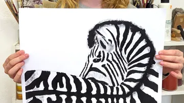 Person, die ein Zebra hält und im Kunstatelier zeichnet.