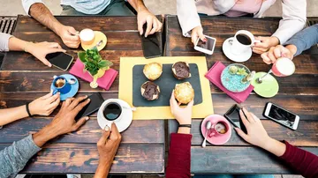People enjoying coffee and muffins at a table.