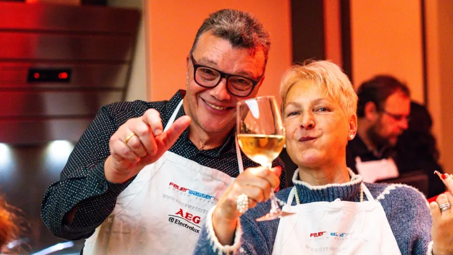 Zwei lächelnde Menschen, die mit Weingläsern toasten.