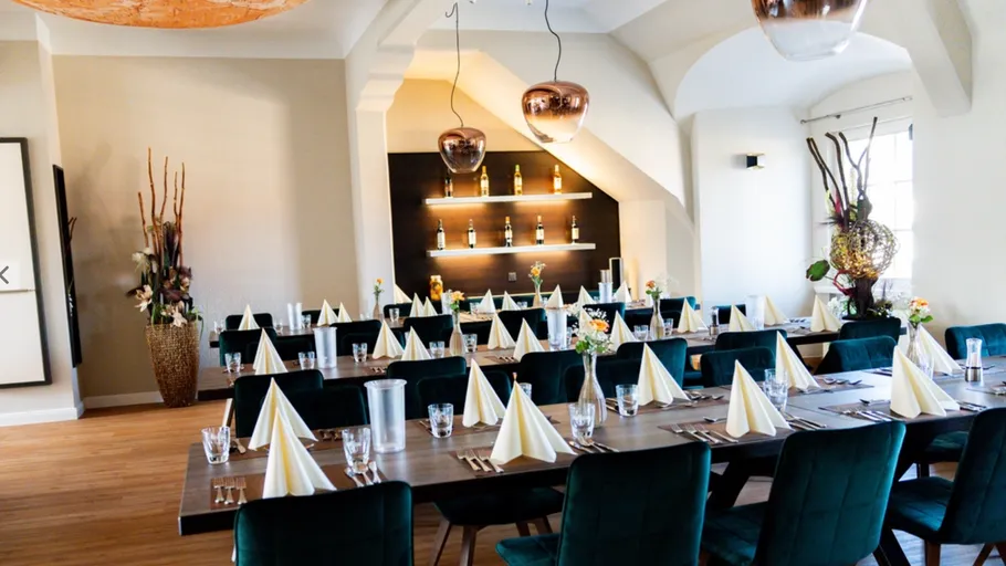 Elegantes Esszimmer mit gedeckten Tischen und dekorativer Beleuchtung.