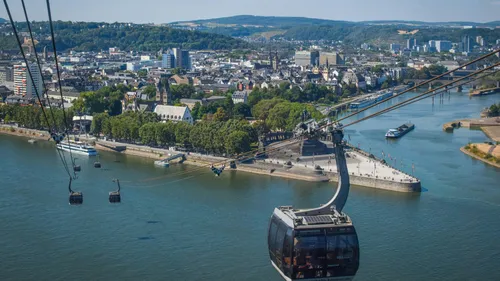 Cable car over river with cityscape background.