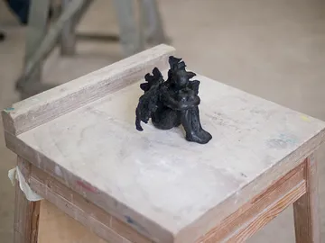 A black sculpture sits on a wooden table.