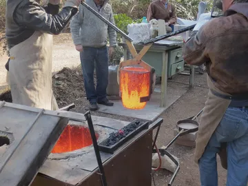Glowing metal is lifted out of the oven with a crane.