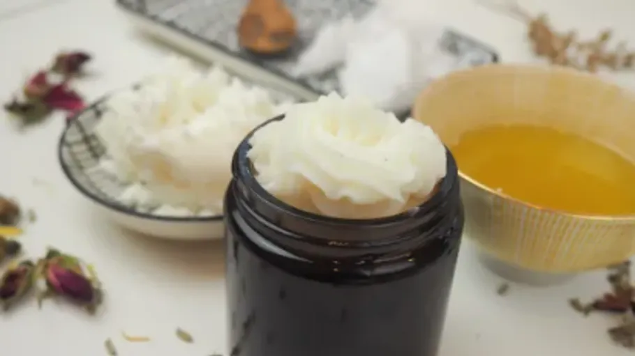 Geschlagene Sheabutter in einem dunklen Glas, umgeben von Zutaten.