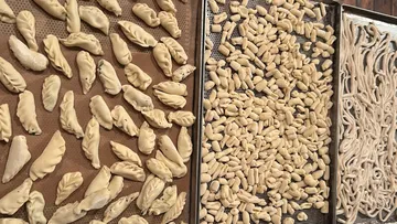 Three trays of handmade pasta shapes drying.