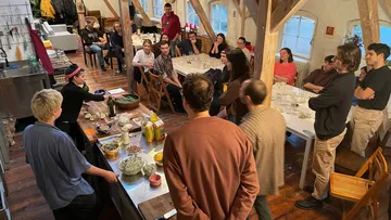 People gather around a table for a cooking demonstration.