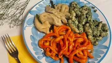 Plate with dumplings, spinach gnocchi, and red pasta.
