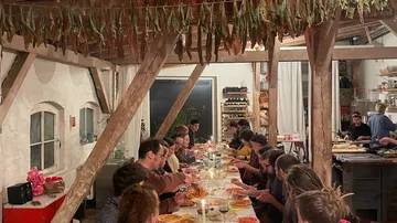People dining at a long table in rustic setting.
