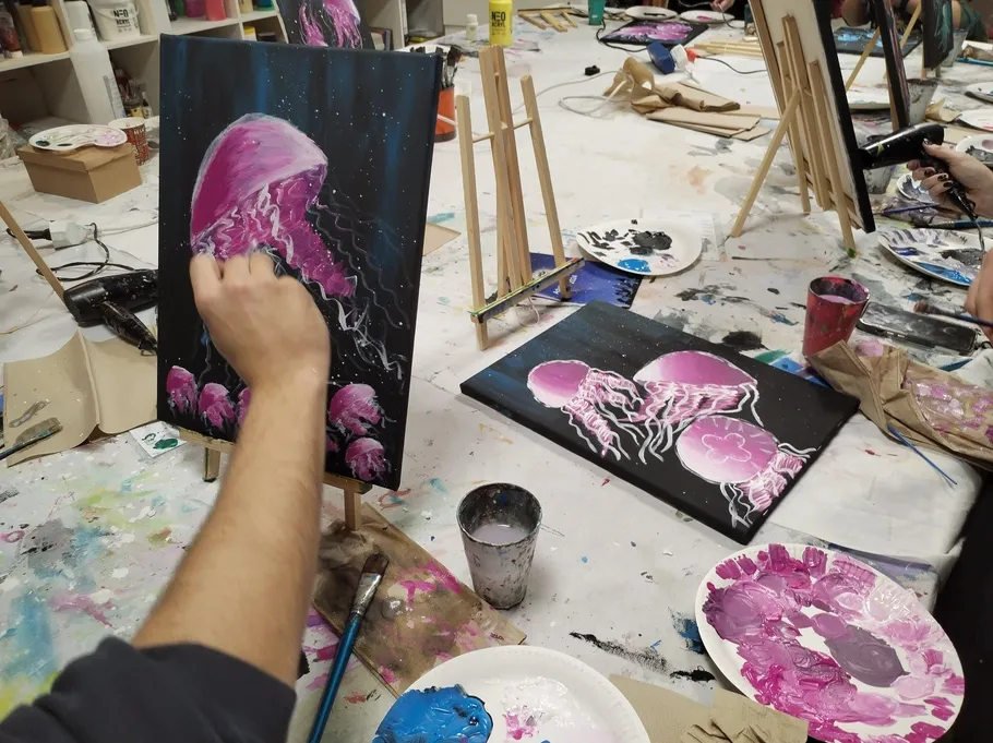 Person painting pink jellyfish on canvas.