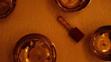 Vier Klangschalen und ein Hammer auf einer weichen Oberfläche.