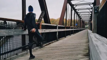 Person stretching on a wooden bridge.