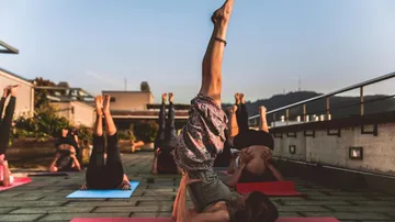 Group practicing yoga headstand on rooftop.