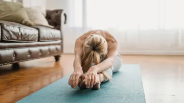 Person stretching on a yoga mat indoors.
