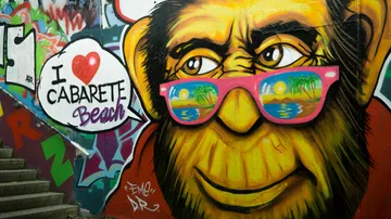 Graffiti of yellow face wearing reflective sunglasses.