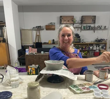 Person painting pottery in art studio.