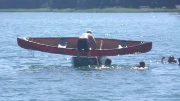 Person flips canoe in water with friends nearby.