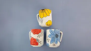 Drei Tassen mit Blumenmustern sind ausgestellt.