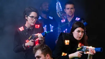 Four people playing laser tag with glowing gear.