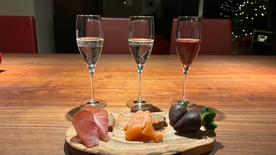 Three champagne glasses with charcuterie board, festive background.
