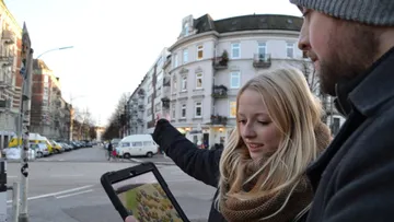 Zwei Personen draußen mit einem Tablet im Stadtgebiet.