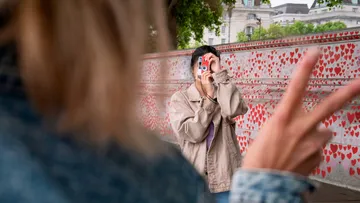 Person, die mit Kamera fotografiert, Wand mit Herzgraffiti.