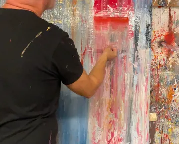 Person, die abstrakte Kunst auf einer Leinwand malt.