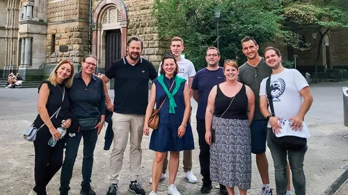 Group of people smiling outdoors, historical building background.