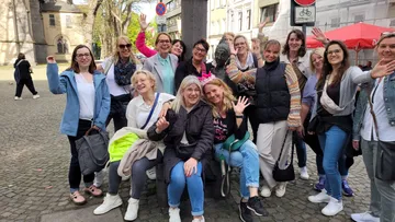 Gruppe von Frauen winkt auf der Kopfsteinpflasterstraße.