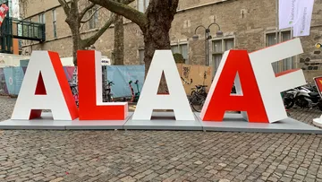 Große rote Buchstaben „ALAAF“ auf der Kopfsteinpflasterstraße.