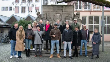 Gruppe von Menschen, die draußen vor der Statue posieren.