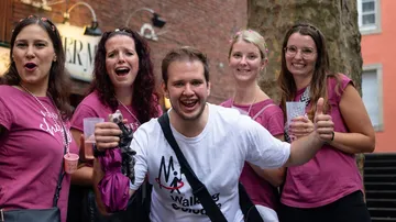 Gruppe lächelnder Menschen in rosafarbenen Hemden im Freien.
