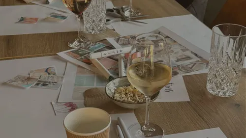 Table with wine, craft materials, and glasses.
