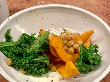 Bowl drizzled with pumpkin, kale, and chickpeas.
