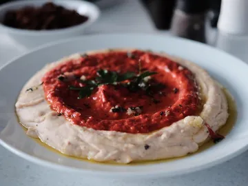 Hummus with red pepper in a shallow dish.