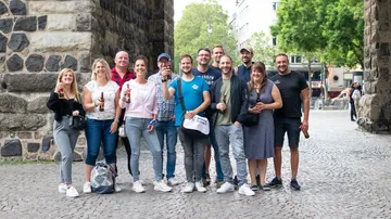 Group of people standing with drinks outdoors.