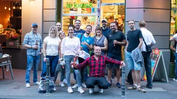 Group of people smiling outside a kiosk.