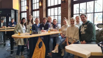 Group of people smiling in a pub setting.