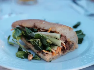 Sandwich with fresh herbs on a white plate.
