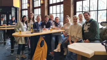 Gruppe von Menschen, die an einem Bartisch lächeln.