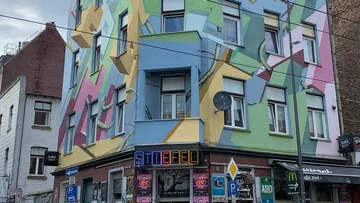 Buntes geometrisches Wandbild an einem Eckgebäude.