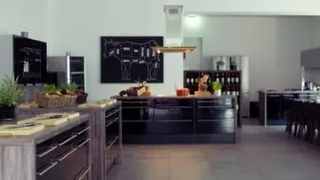 Moderne Küche mit schwarzen Schränken und Kräutern.