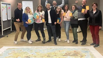 Group celebrating with books and a map.